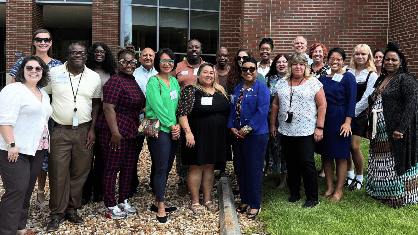 Diverse group of 21 public health professionals posting outside a building