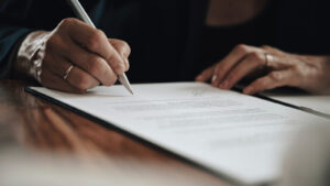 Someone signing a piece of paper with a pen
