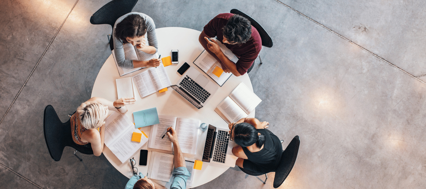 Birds eye view of people sitting around a table working on laptops