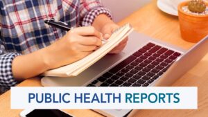 A male student taking notes with a pen and pad near a laptop