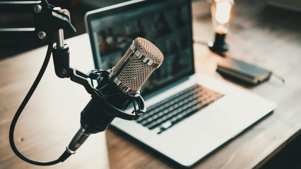 Open laptop next to a microphone used for podcasting