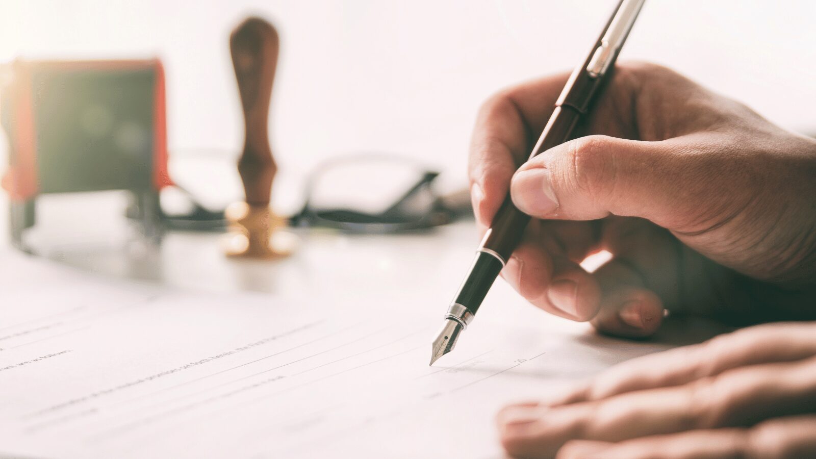 A hand holding a pen over a piece of paper