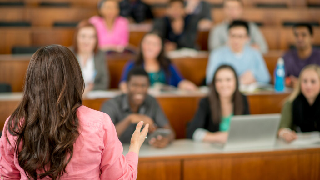 Professor addressing a diverse group of students in a university lecture hall, engaging them in discussion