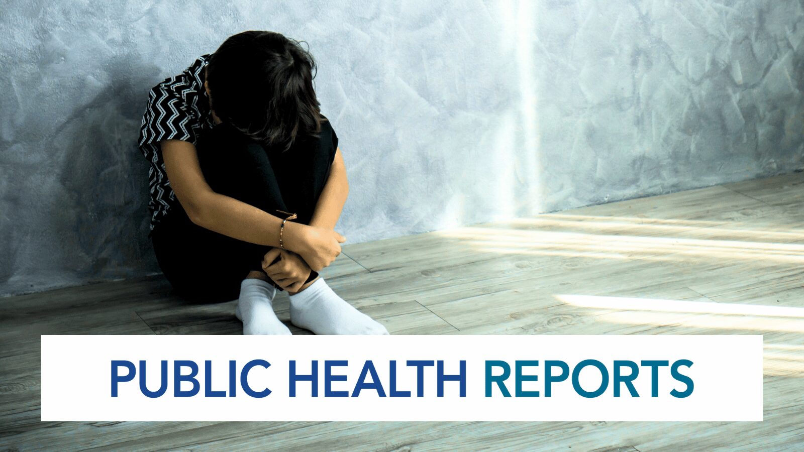 Sad child sitting on the floor hugging knees, with public health reports text overlay