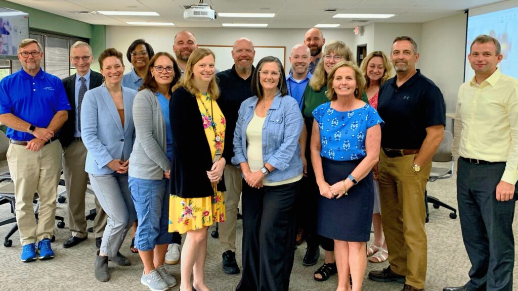 Group photo of faculty and staff during the Wright State University visit, standing in a classroom with a projector in the background
