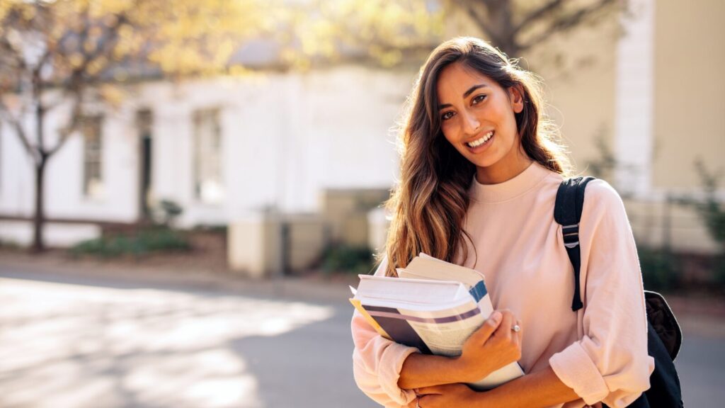 stock image of student carrying books and a backpack