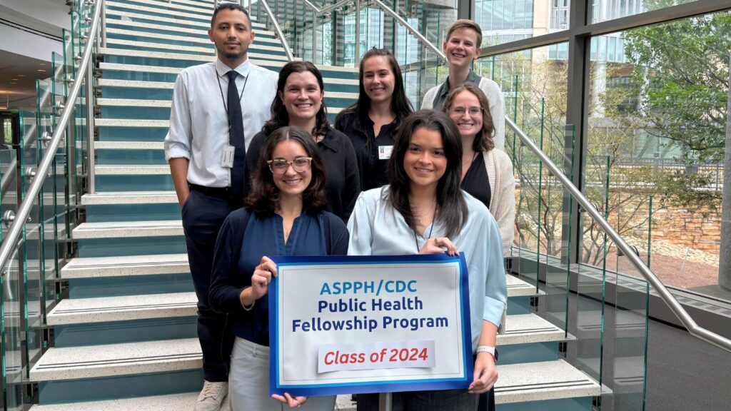 Group photo of eight ASPPHCDC Public Health Fellowship Program fellows, Class of 2024, standing on a staircase. Two fellows hold a program sign