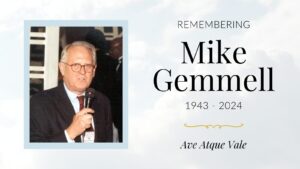 A memorial image for Mike Gemmell (1943-2024) showing an older man with glasses and white hair wearing a dark suit and red tie, speaking into a microphone, with 'Ave Atque Vale' below