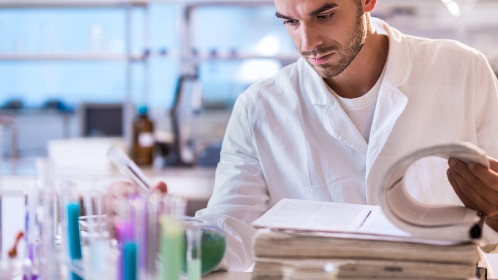 scientist in a lab coat analyzing test tubes and research documents in a laboratory setting