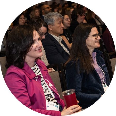 Two people sat in an audience and smiling