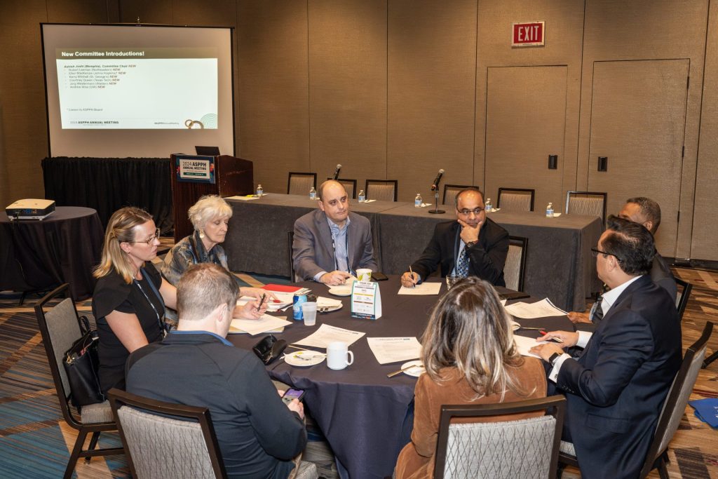 Group of committee members conversing around a table.