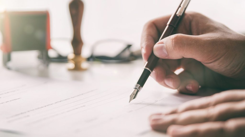 close up image of person signing a letter with pen