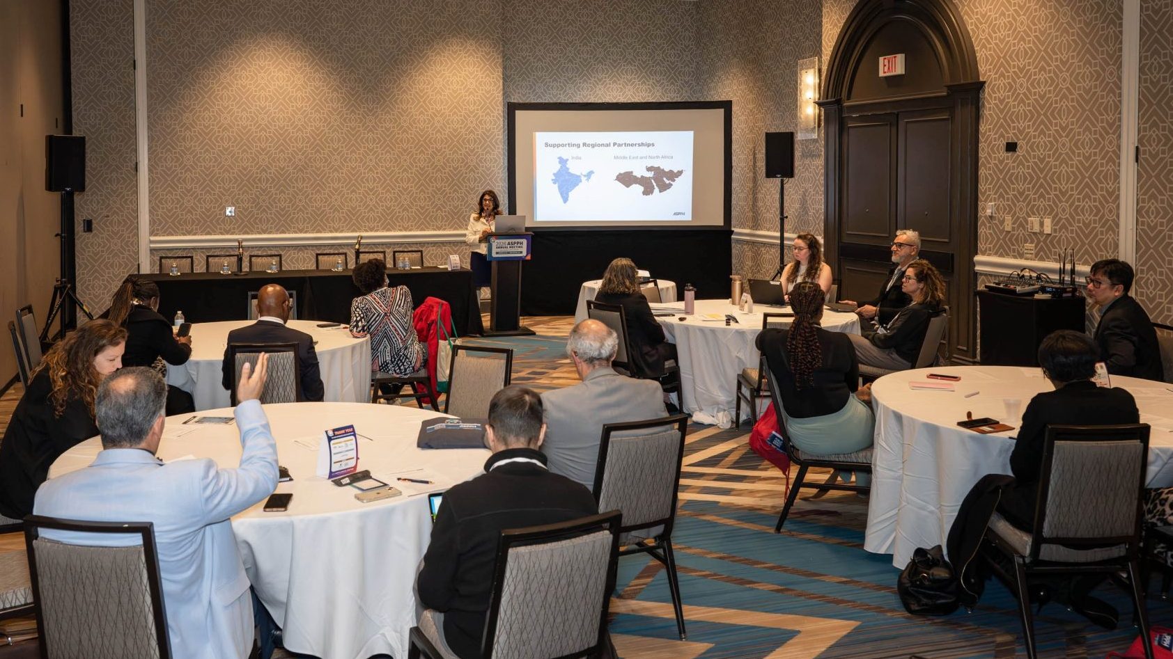 Four tables filled with people watching a presentation