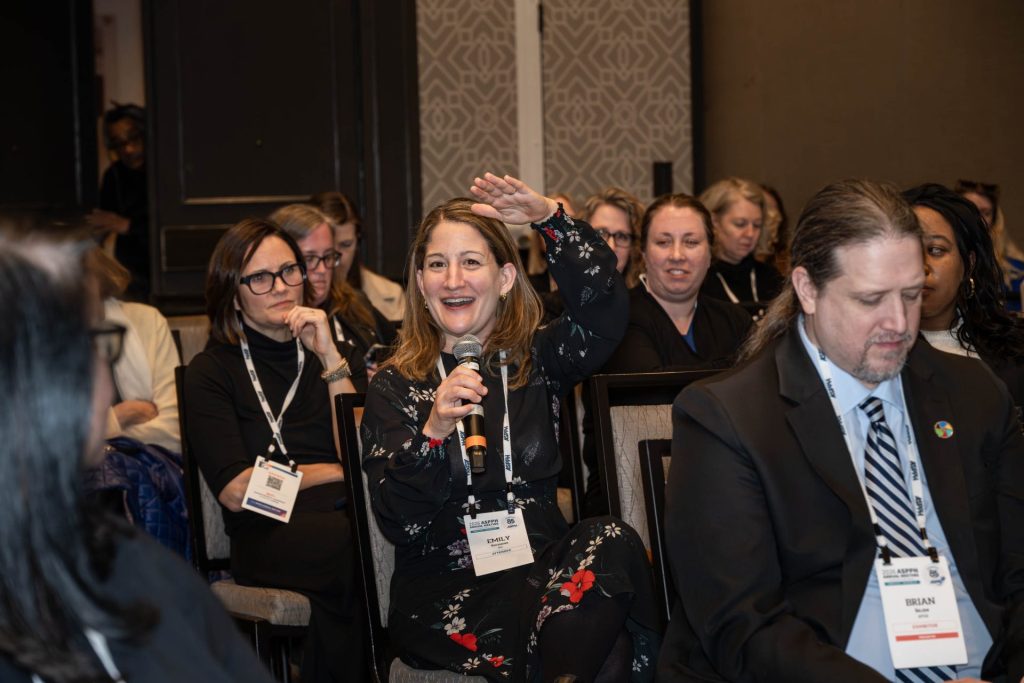 Woman speaks into a microphone in a room full of people