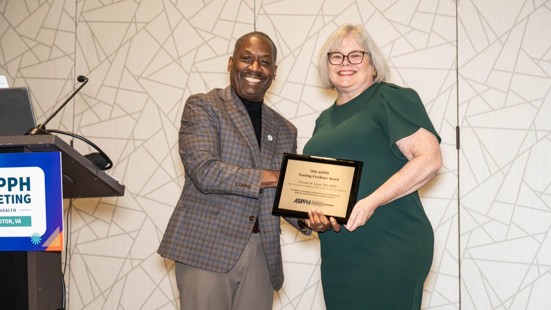 A man and woman stand holding an award