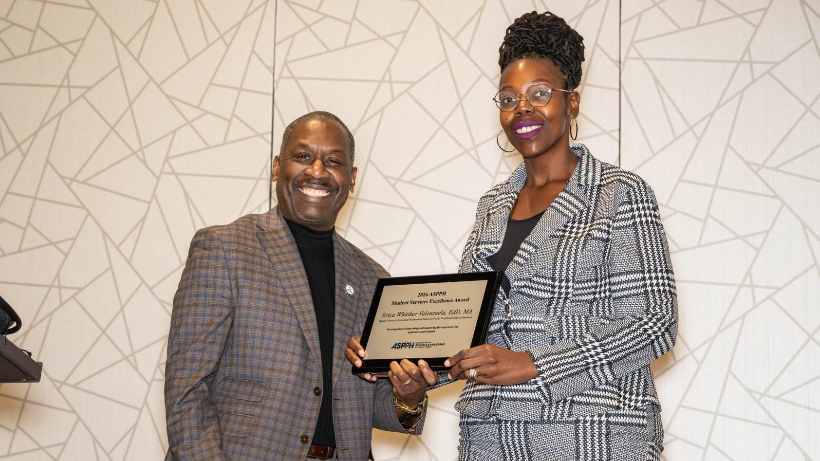 A woman holding an award stands next to a man