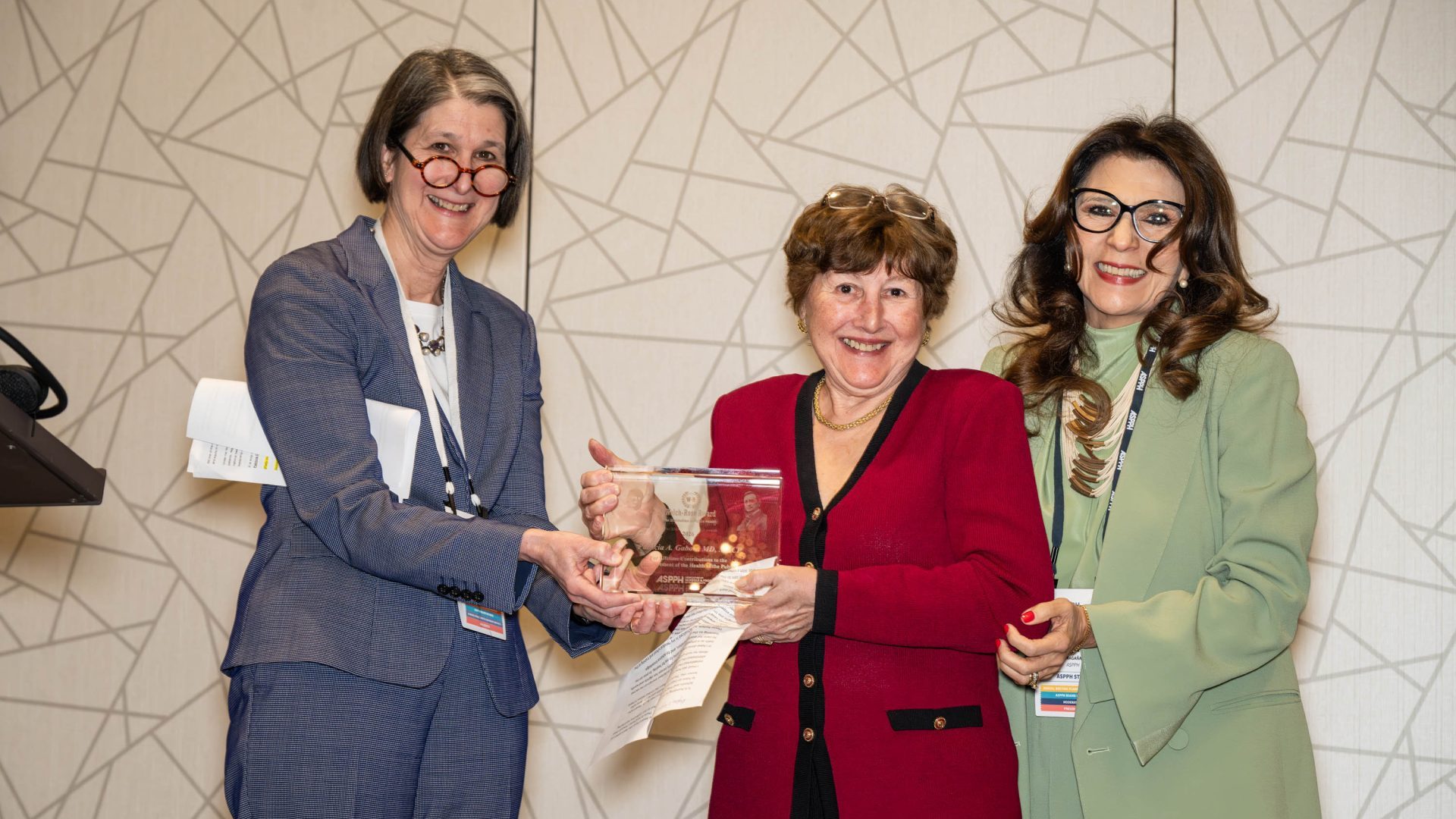 A group of women stand with one holding an award