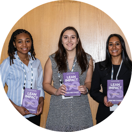 Three women each holding a purple book titled "Lean Impact"