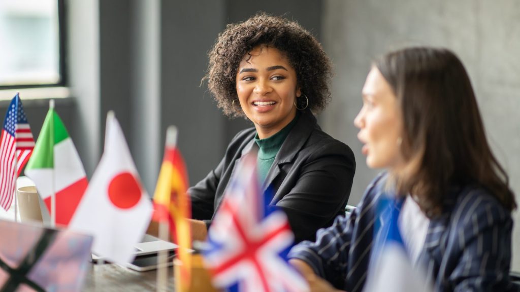 Two women sitting at table with international flags