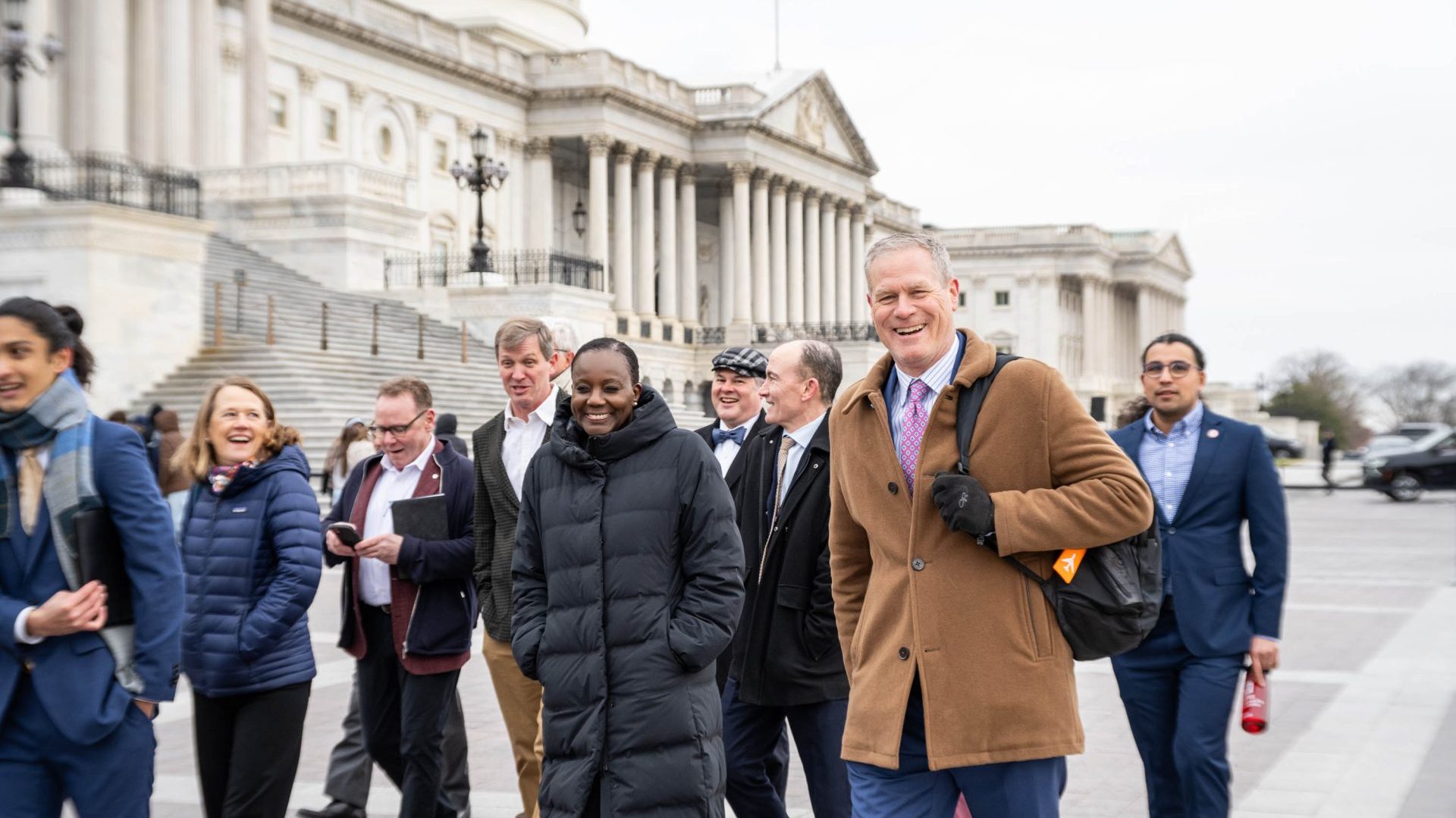 A group of people walking in front of the US Capitol