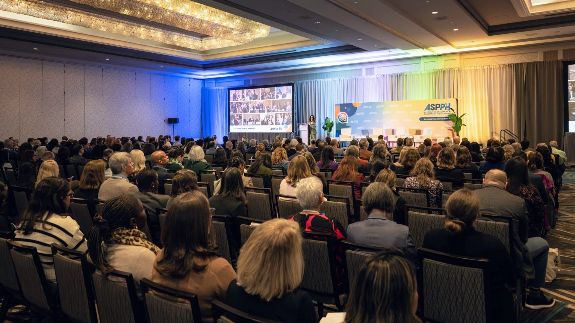 An audience sits and watches the opening remarks to a conference