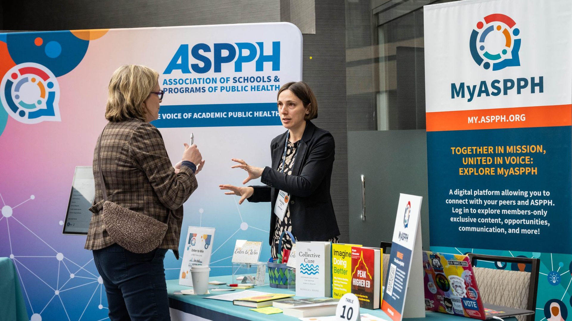 Rep at MyASPPH table speaking with an event attendee