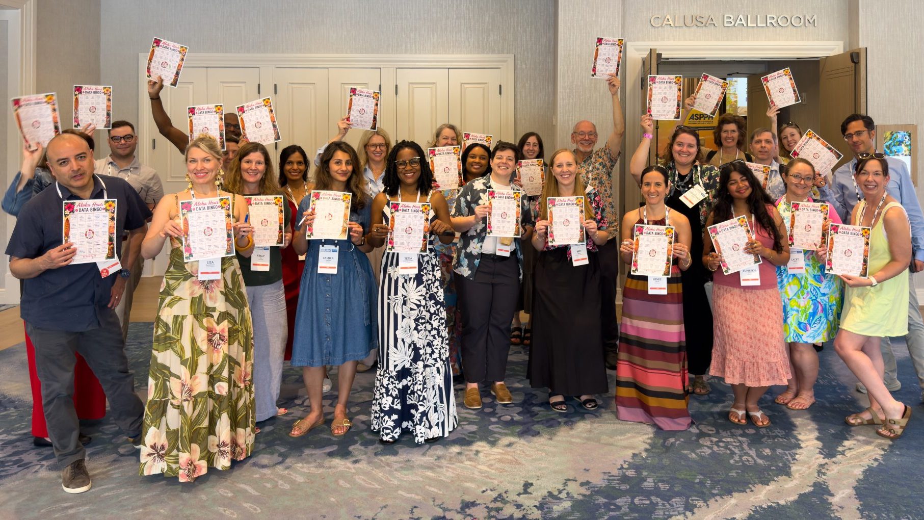 A group of people smiling and posing with pieces of paper