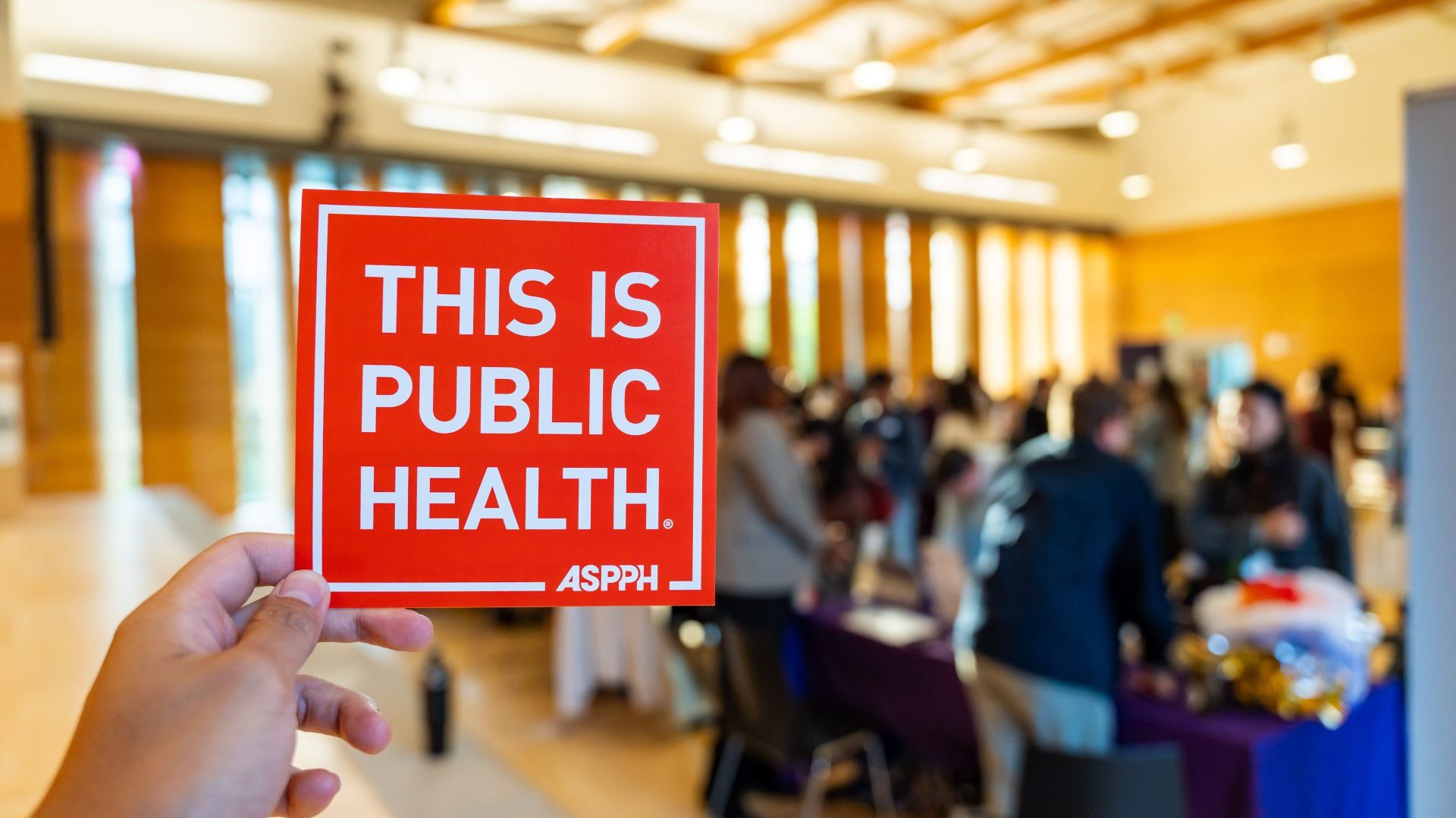 A person holding up a 'This Is Public Health' postcard
